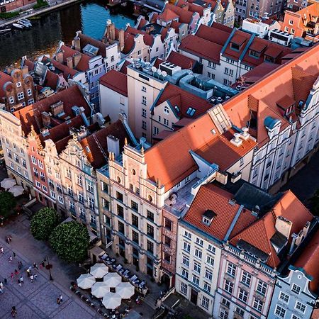 格但斯克，雷迪森布鲁酒店 外观 照片 The photo shows a bird's-eye view of a picturesque urban area, likely in a historical city. It features a cluster of buildings with a mix of architectural styles, characterized by colorful facades and predominantly red rooftops. The buildings seem to