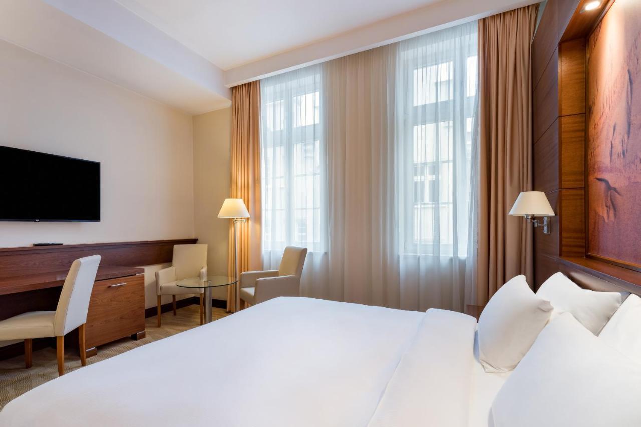 格但斯克，雷迪森布鲁酒店 外观 照片 The photo depicts a modern hotel room. It features a neatly made bed with white linens, flanked by two pillows. On the wall opposite the bed, there is a flat-screen television mounted. There are two windows with sheer curtains that allow natural ligh
