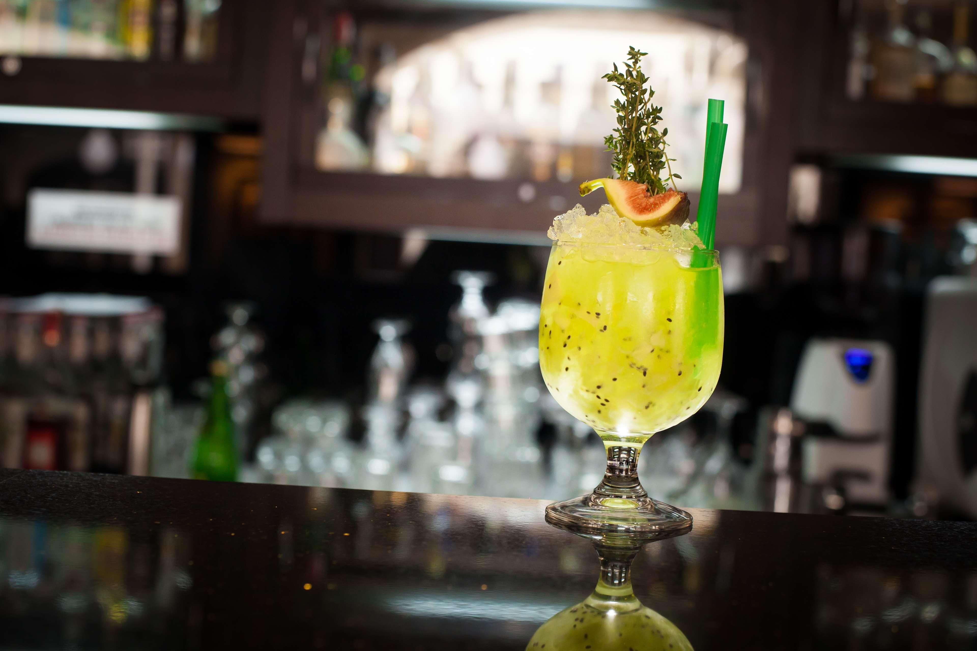 格但斯克，雷迪森布鲁酒店 外观 照片 The photo shows a vibrant, green cocktail served in a stylish glass with a wide base and an elegant stem. The drink is garnished with a slice of fruit and a sprig of herbs, adding visual appeal. A green straw is inserted into the drink, and it appear