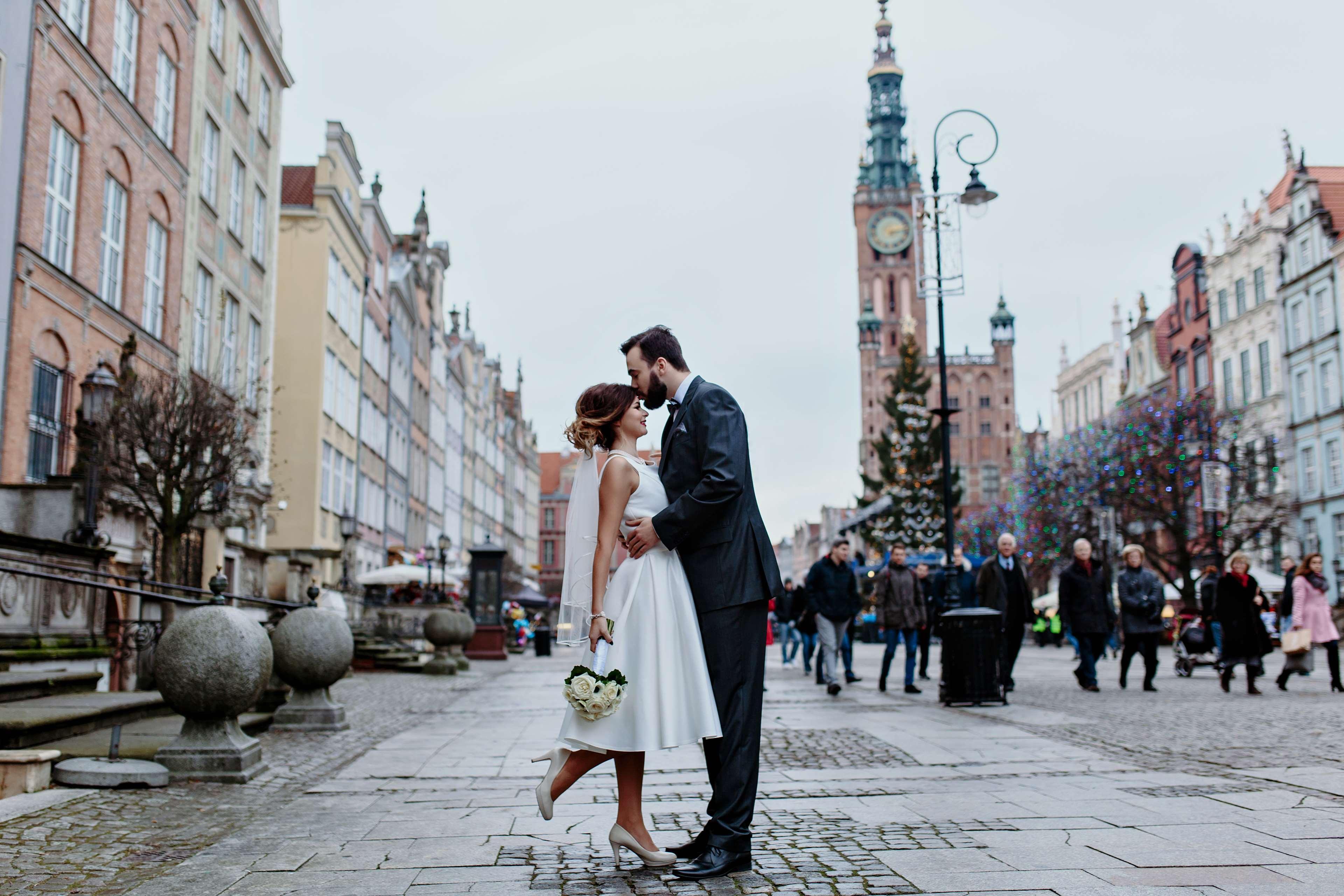 格但斯克，雷迪森布鲁酒店 外观 照片 The photo depicts a joyful moment between a couple in a romantic embrace on a lively street. The woman is wearing a white wedding dress, and the man is dressed in a smart suit. They appear to be celebrating their love, possibly on their wedding day. 