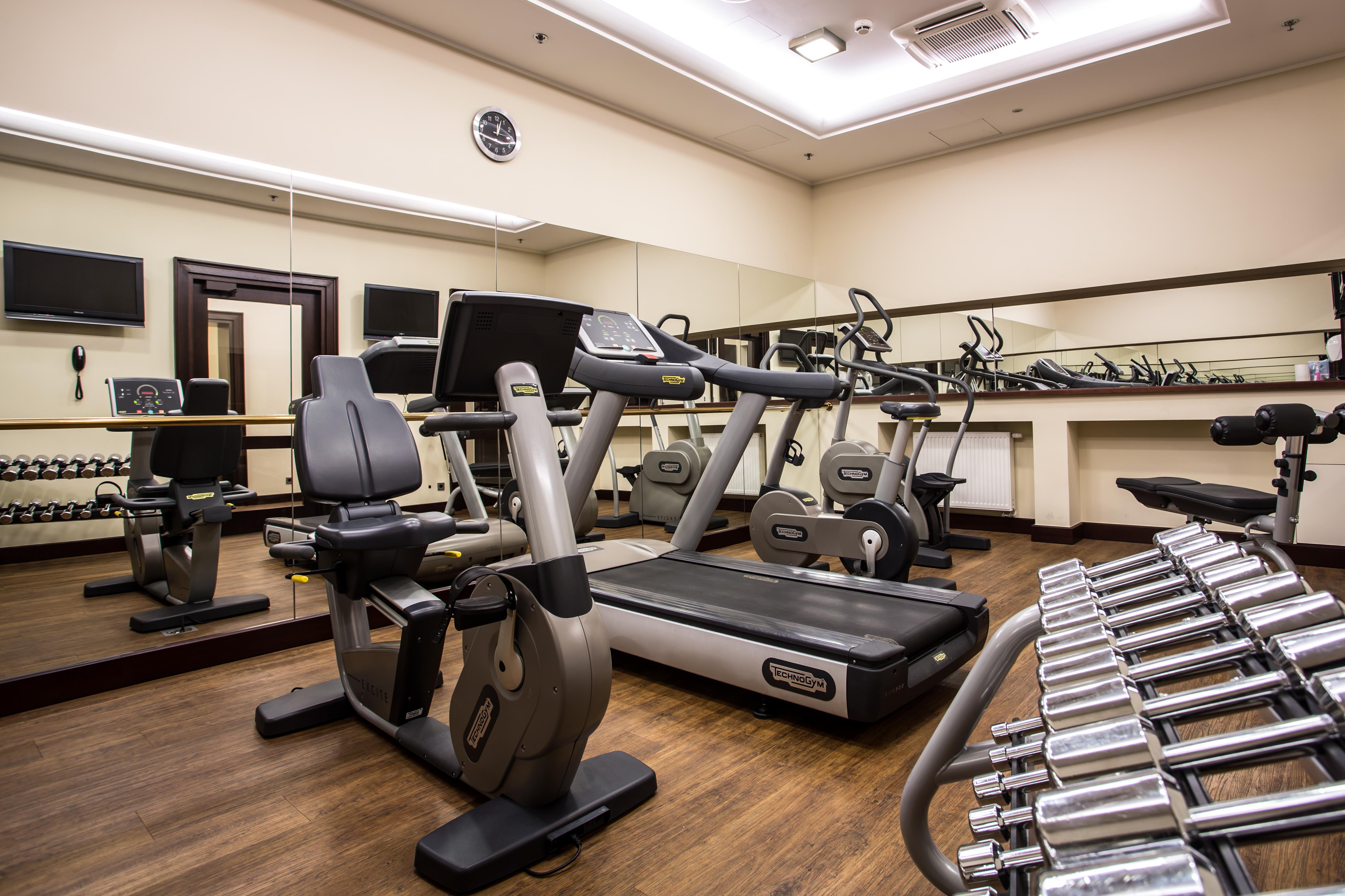 格但斯克，雷迪森布鲁酒店 外观 照片 The photo displays a small gym or fitness room. The room features various exercise equipment, including a treadmill, an elliptical machine, and a set of dumbbells arranged on a rack. There are mirrors on the wall, which help create a sense of space a
