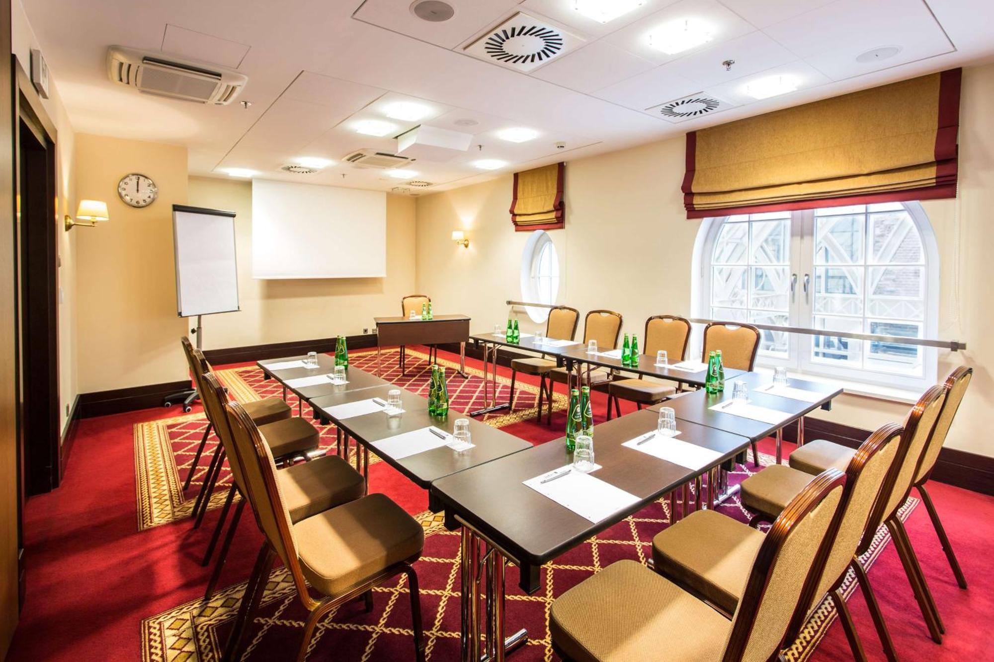 格但斯克，雷迪森布鲁酒店 外观 照片 The photo shows a conference room set up for a meeting. It features a large rectangular table surrounded by several chairs. On the table, there are bottles of water and paper notepads for participants. A flip chart is positioned at one side of the ro