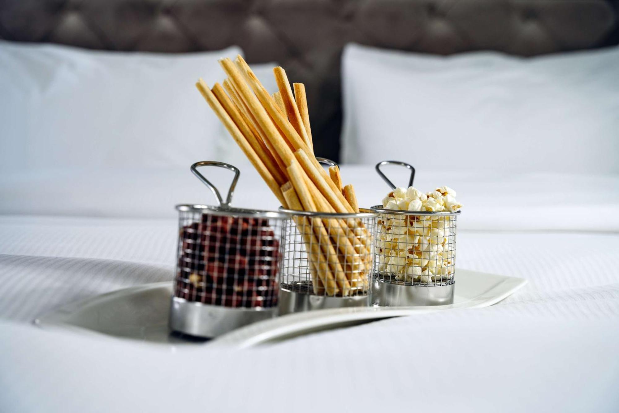 格但斯克，雷迪森布鲁酒店 外观 照片 The photo shows a tray with three small metal baskets. Each basket contains a different type of snack. 

1. The first basket holds breadsticks, which are long and thin, arranged upright.
2. The second basket contains what appears to be chocolate-cove