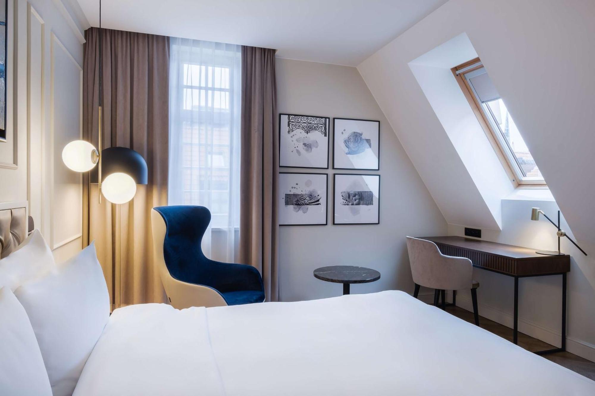 格但斯克，雷迪森布鲁酒店 外观 照片 The photo shows a cozy hotel room featuring a modern design. The room has a double bed with a white duvet, and a large window with sheer curtains that allows natural light to filter in. On the wall opposite the bed, there are several framed artworks.