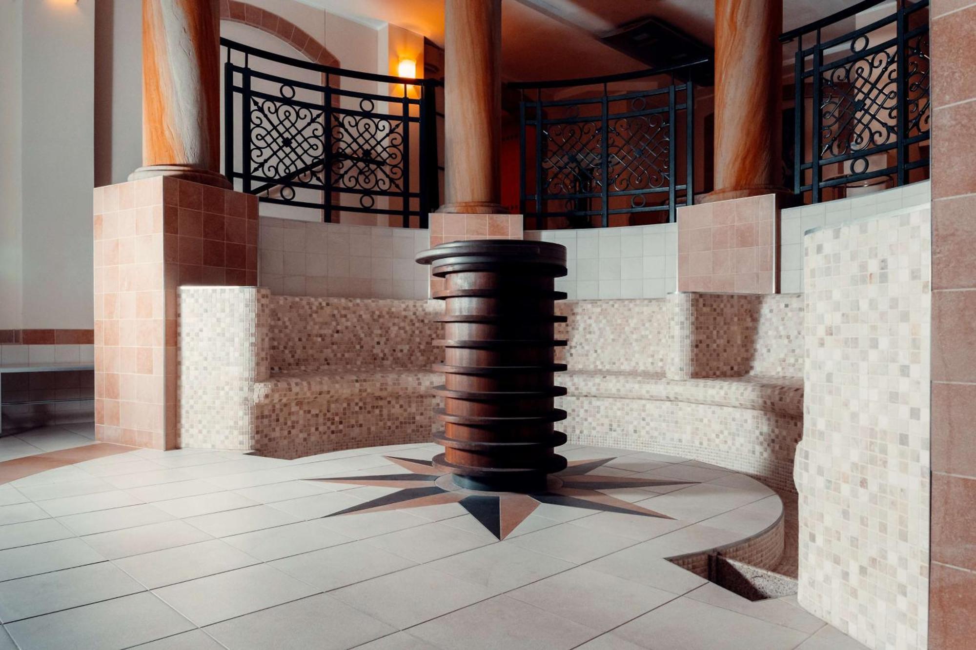 格但斯克，雷迪森布鲁酒店 外观 照片 The photo showcases a well-designed interior space, likely part of a spa or wellness center. In the center, there is a circular seating area made of tiled blocks arranged in a semicircular pattern. The floor features a star-shaped design with contras