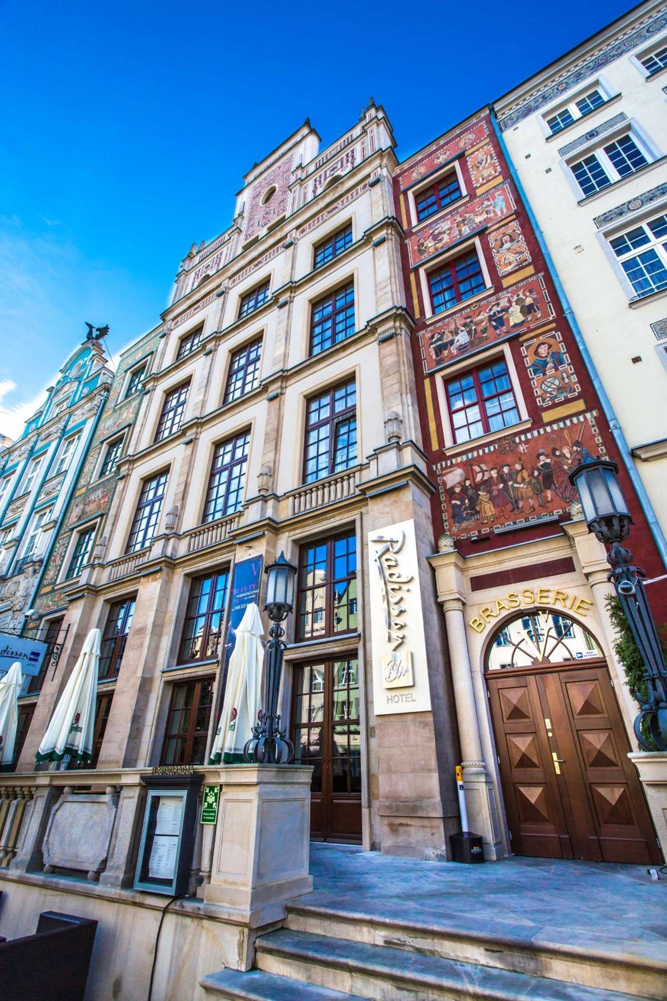 格但斯克，雷迪森布鲁酒店 外观 照片 The photo shows a historic building with a richly decorated facade. The architecture features large windows and intricate details, including murals or painted scenes on the walls. There is a sign that indicates a brasserie, suggesting that this locat