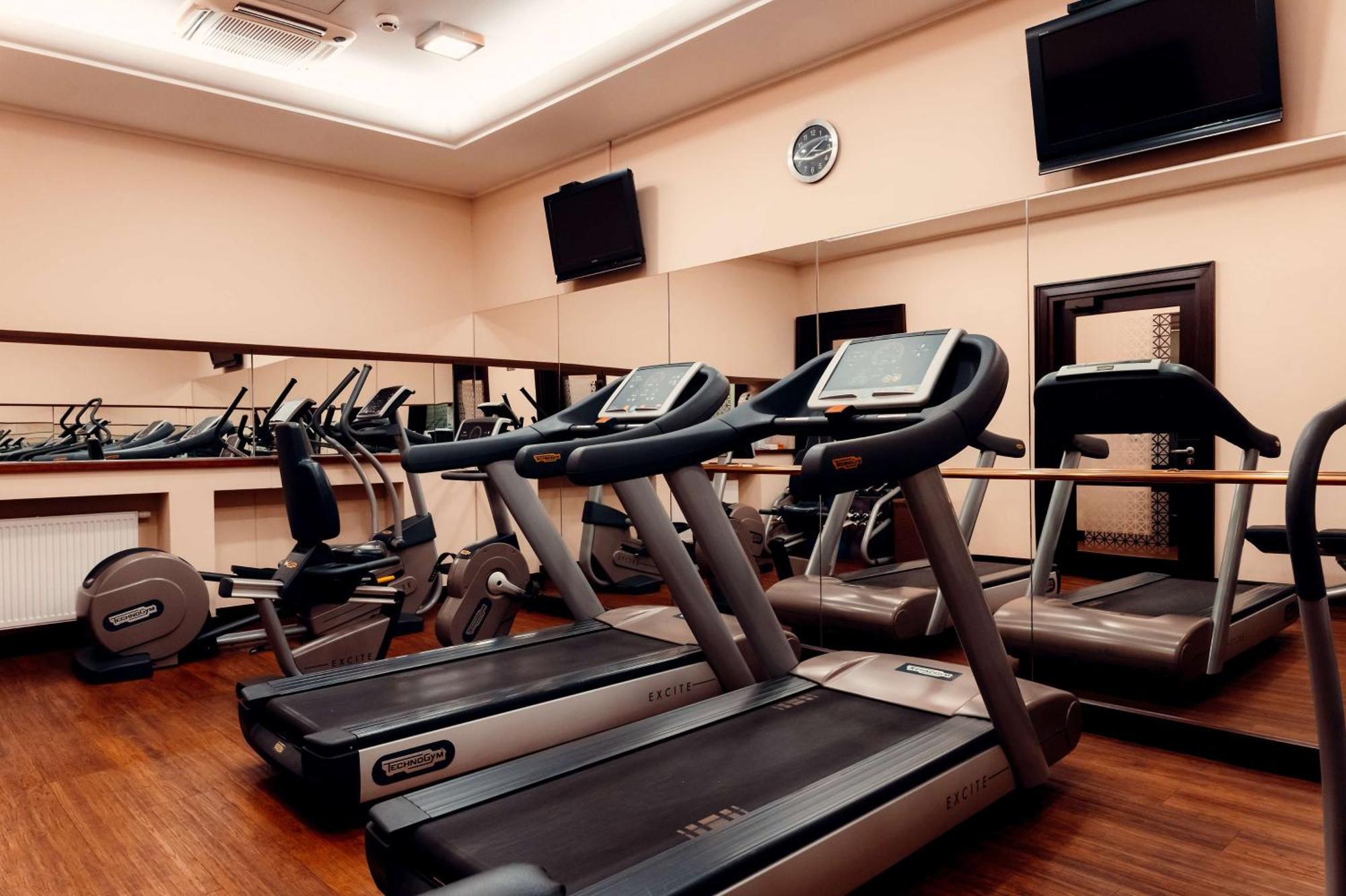 格但斯克，雷迪森布鲁酒店 外观 照片 The photo shows a gym or fitness center with several exercise machines. There are multiple treadmills lined up in the foreground, each equipped with a display screen. In the background, there are additional fitness machines, including stationary bike